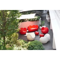 Un canapé Blossy rouge sur une terrasse avec d'autres fauteuils de couleurs rouges et blancs