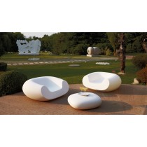 Deux fauteuils blancs avec un table basse assorties sur la terrasse d'un jardin.