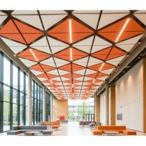 Suspensions acoustiques Triums orange et blanches formant un plafond géométrique dans un grand hall lumineux.