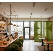 Parois acoustiques Fragma Flow vertes suspendues dans un café au design naturel et lumineux.