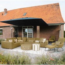 Canapé d'angle extérieur Teton vert olive sur terrasse dallée, avec poufs ronds, fauteuils lounge et parasol déporté
