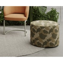 Pouf de jardin Peak à motif kaki et vert sur un tapis gris à chevrons, devant un fauteuil orange et du feuillage