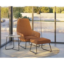 Fauteuil lounge extérieur Flux orange avec repose-pieds assorti, près d'une baie vitrée donnant sur une piscine