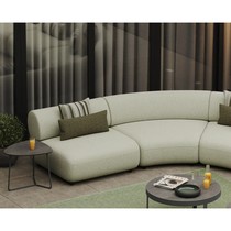Canapé arrondi Onyx vert clair dans un salon, avec coussin vert et table d'appoint