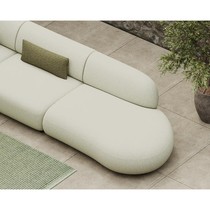 Détail de l'extrémité arrondie du canapé Onyx vert clair, avec coussin vert posé sur le dossier