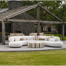 Canapé rond extérieur Onyx blanc cassé en courbe sur une terrasse, devant une pergola en bois